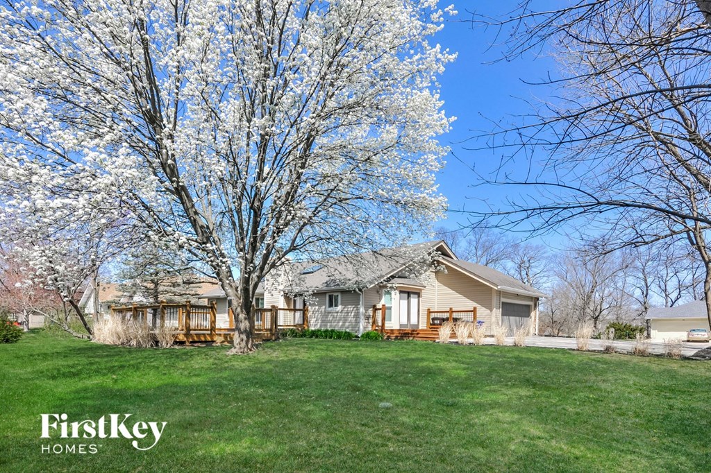 A house with a tree in bloom in front of it.