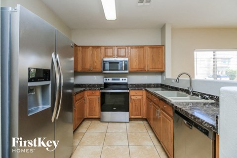 A kitchen with a refrigerator, microwave, oven, sink and cabinets.