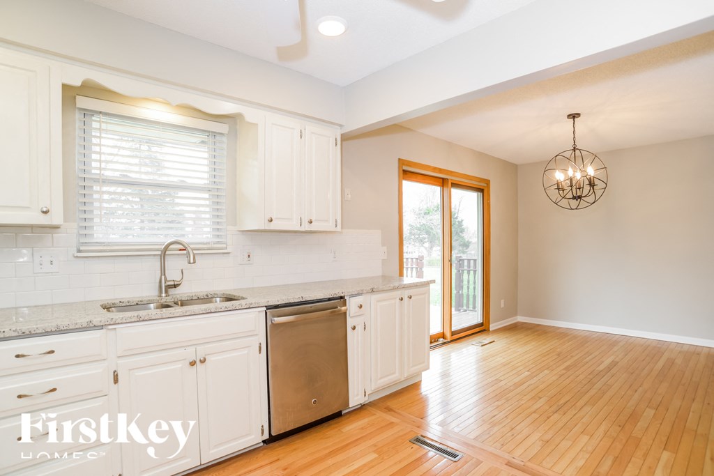 a kitchen with white cabinets and a sink and a door to a balcony