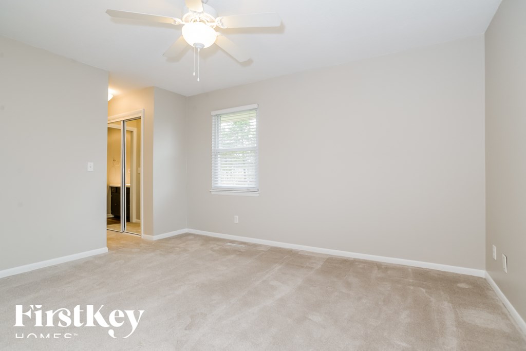 the spacious living room with carpet and a ceiling fan
