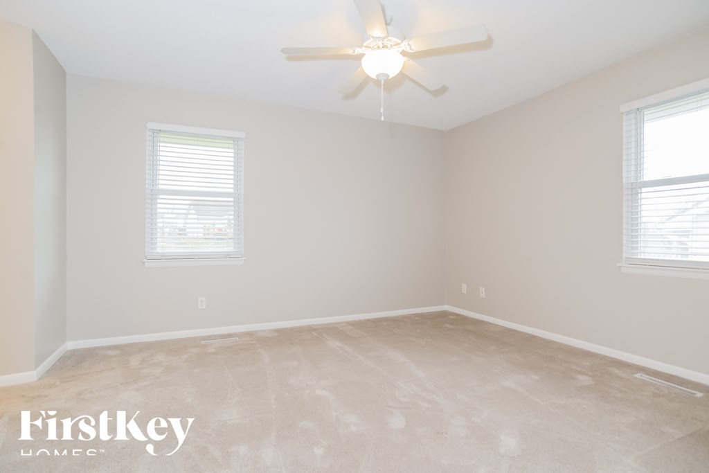 a empty room with a ceiling fan and two windows