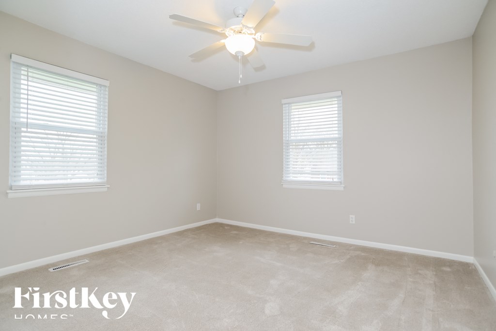 a bedroom with a ceiling fan and two windows