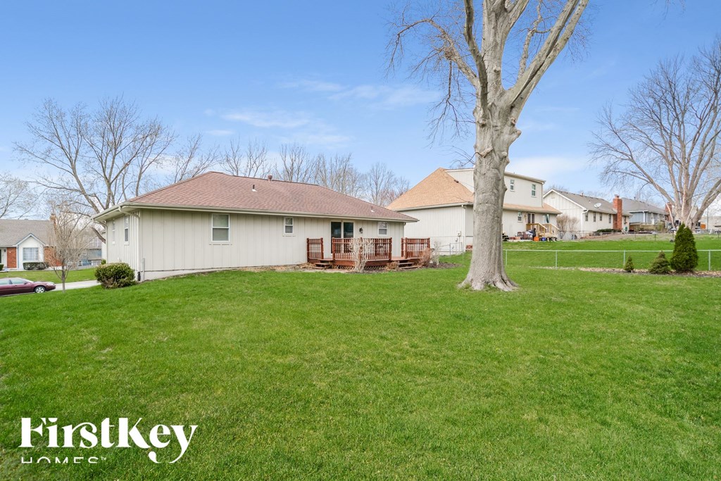 a backyard with a tree and a white house