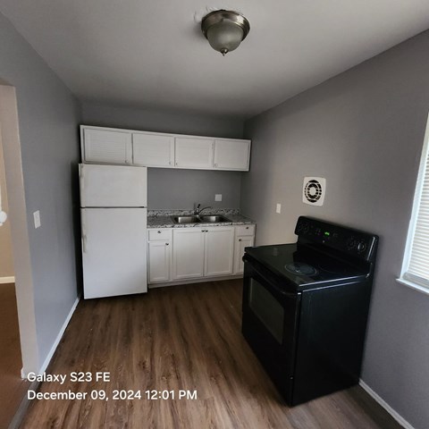 A kitchen with a black stove top oven and white appliances.