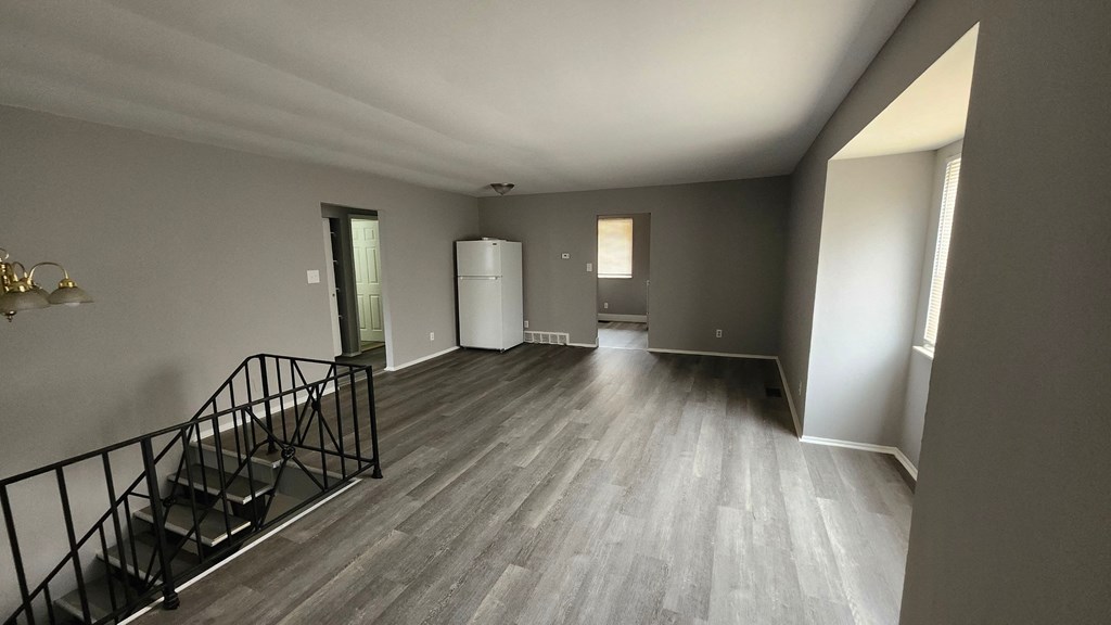 A spacious room with a staircase and a white refrigerator.