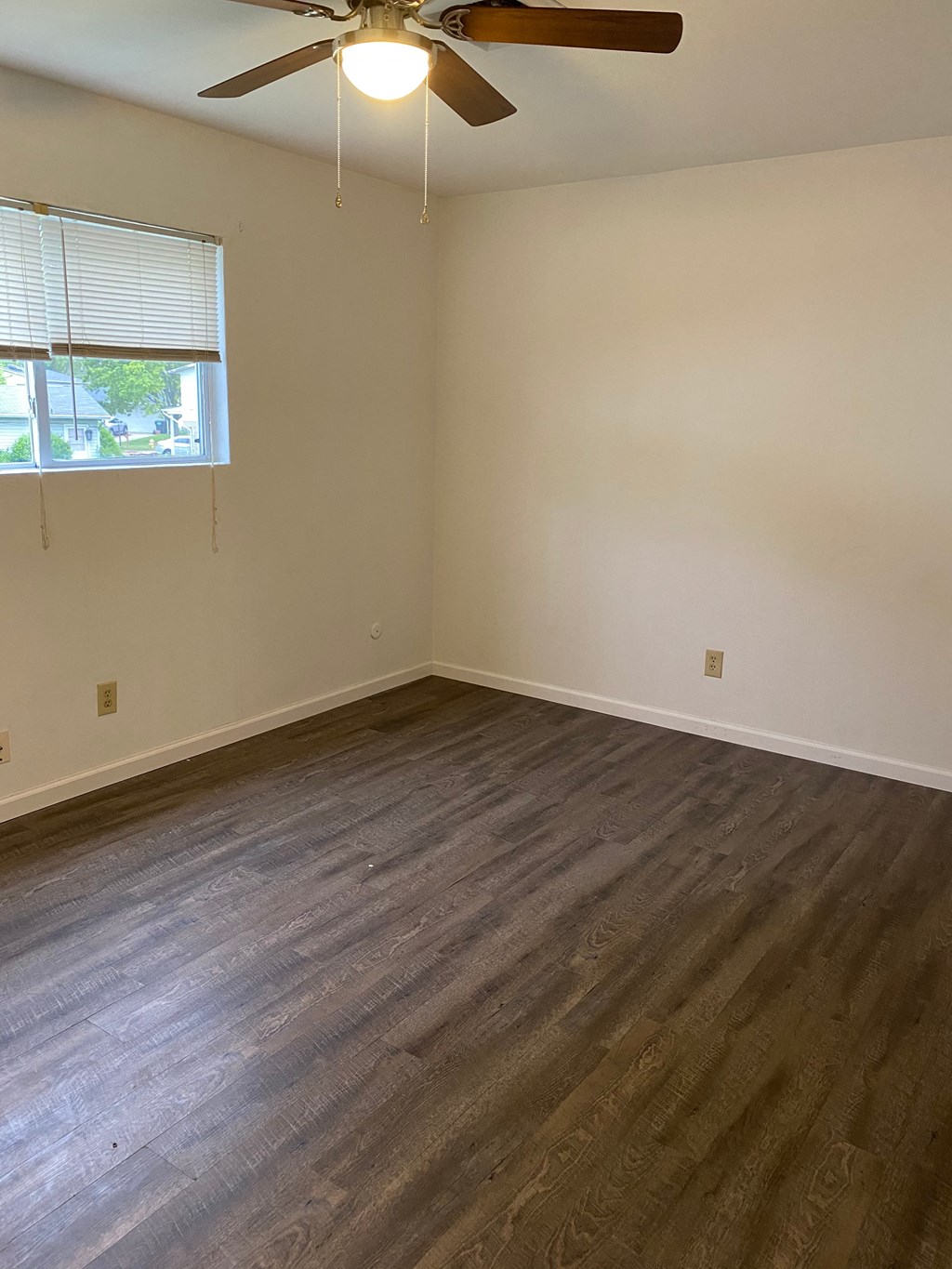 an empty living room with wood floors and a ceiling fan