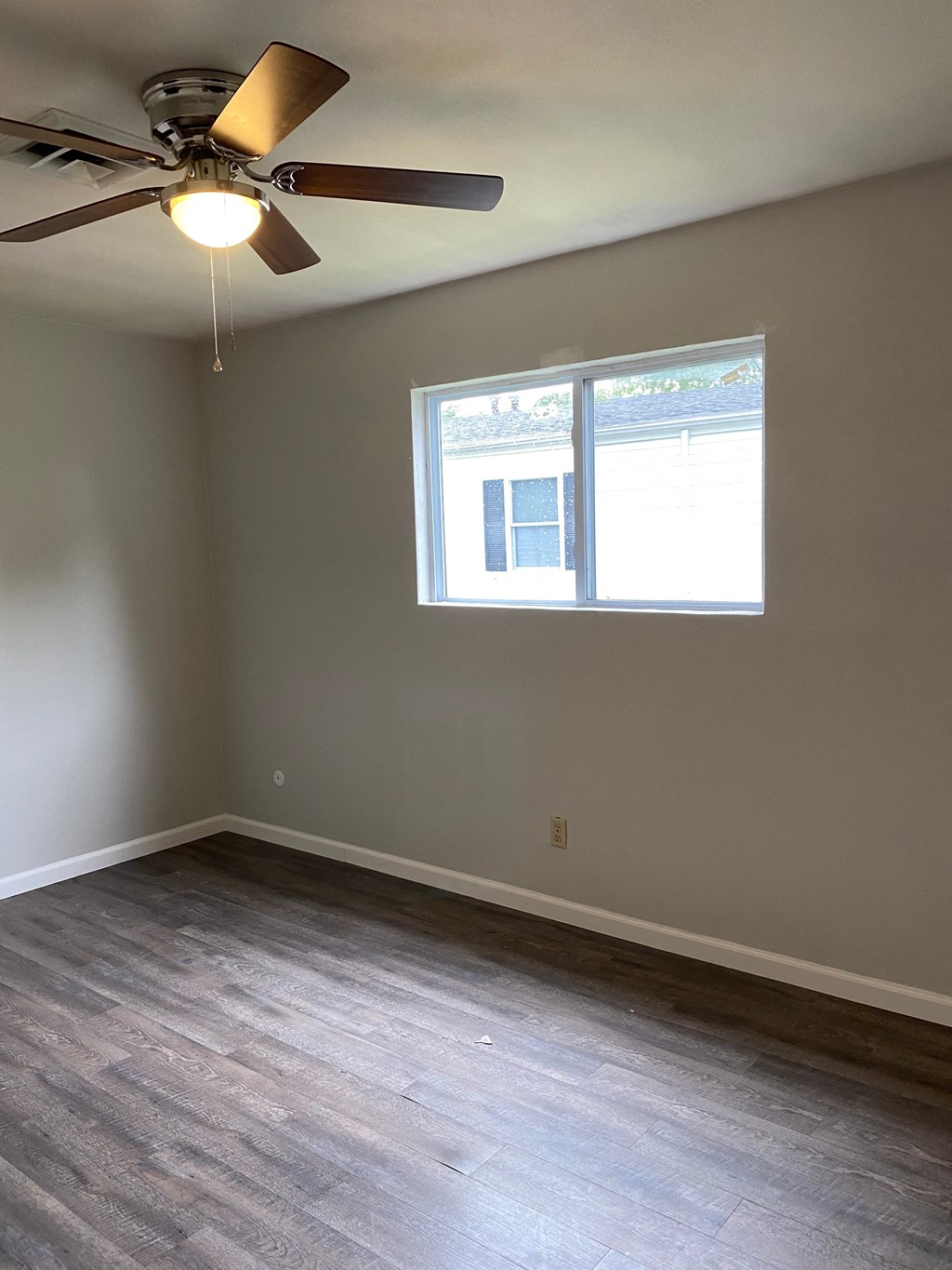an empty room with a ceiling fan and a window