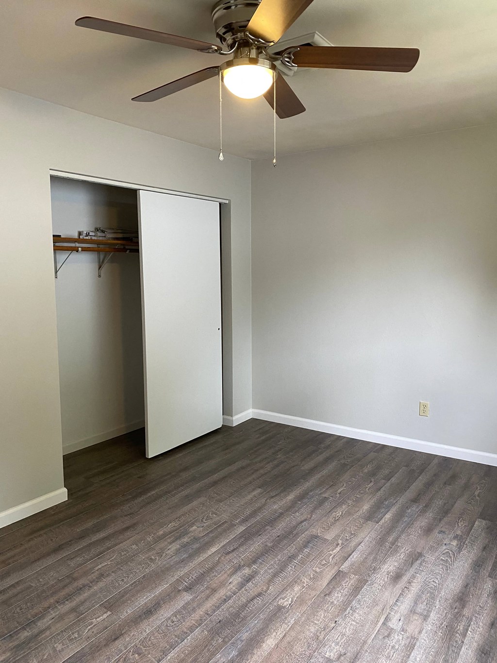 an empty living room with a ceiling fan and a closet