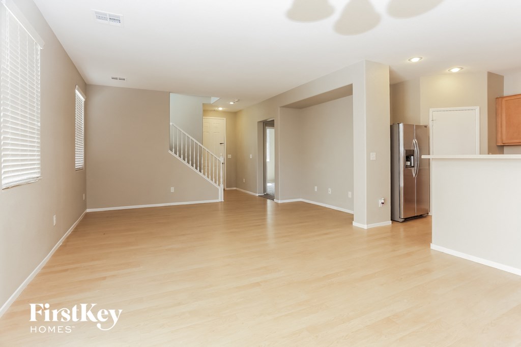 an empty living room and kitchen with a stainless steel refrigerator