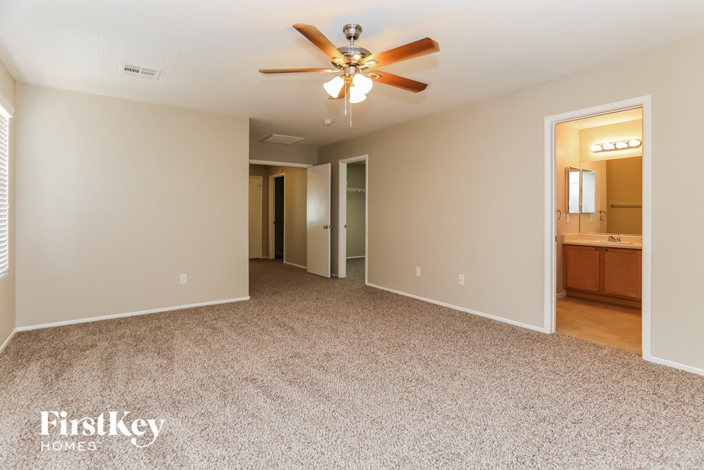 a spacious living room with carpeting and a ceiling fan