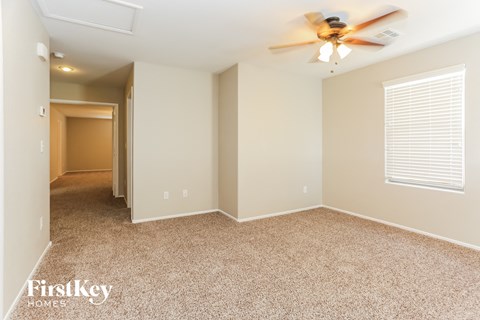a spacious living room with carpet and a ceiling fan