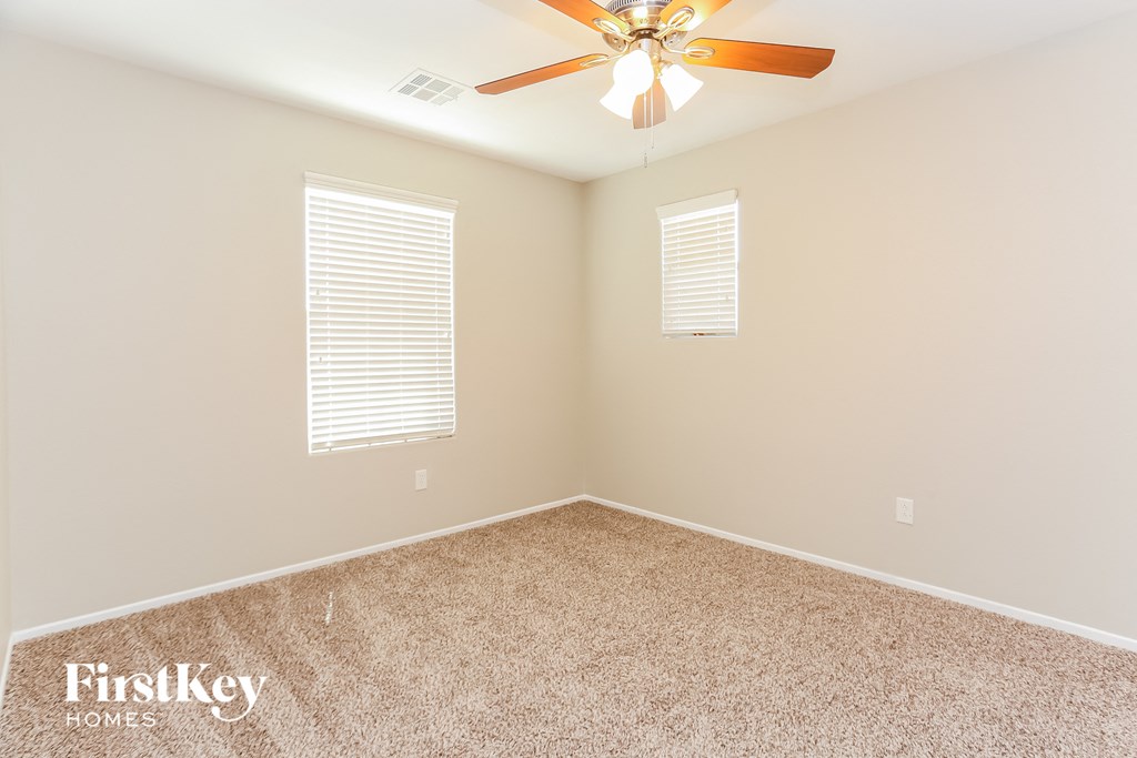 a empty room with a ceiling fan and two windows