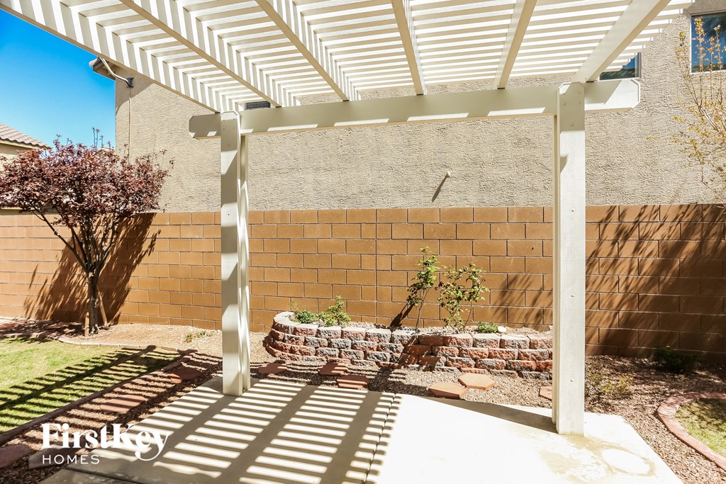 a pergola in a backyard with a brick retaining wall