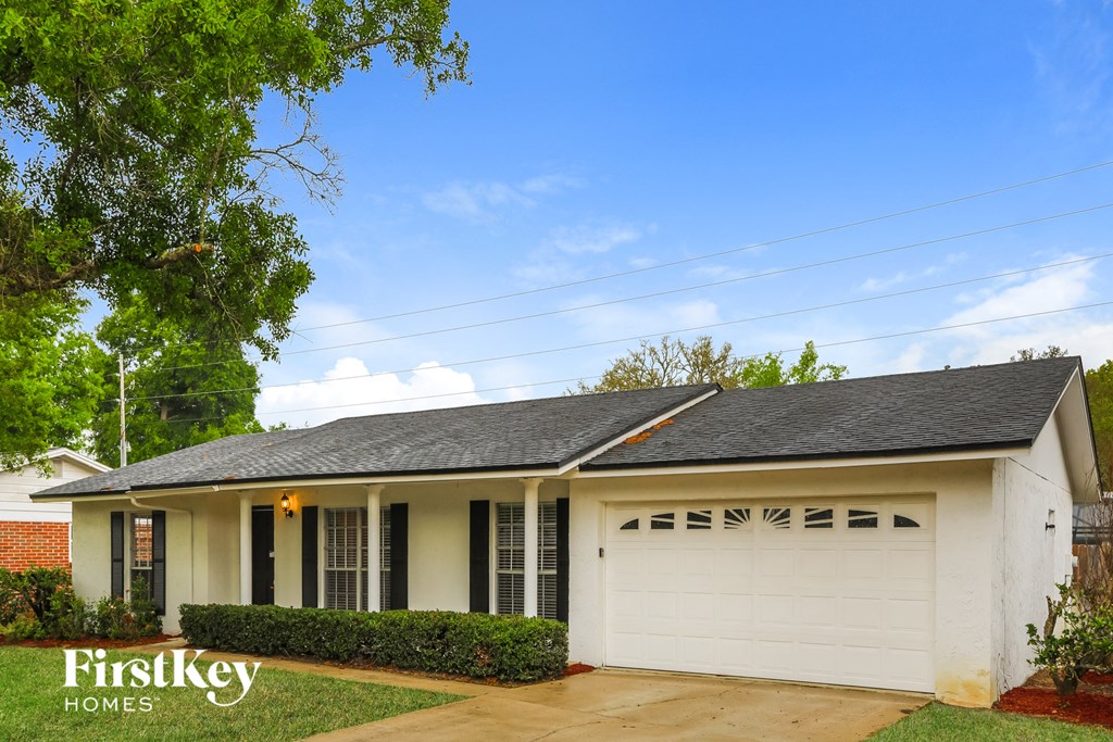 A white house with a black roof and a garage door is shown.