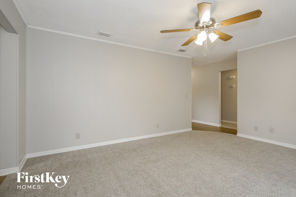 A spacious room with a ceiling fan and carpeted floor.