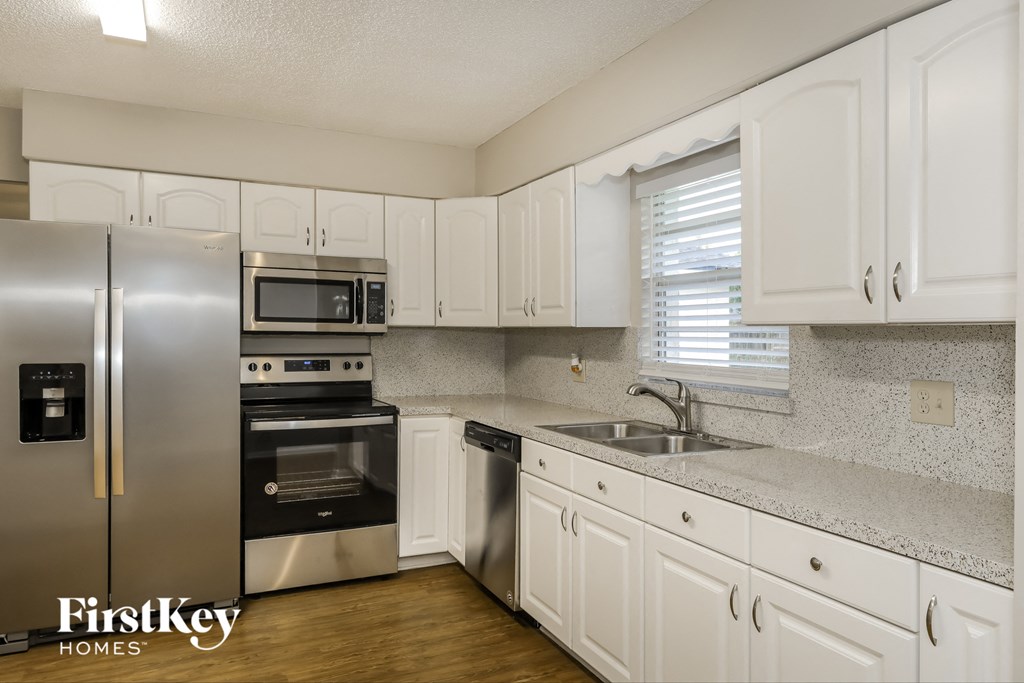 A kitchen with white cabinets and a stainless steel refrigerator.
