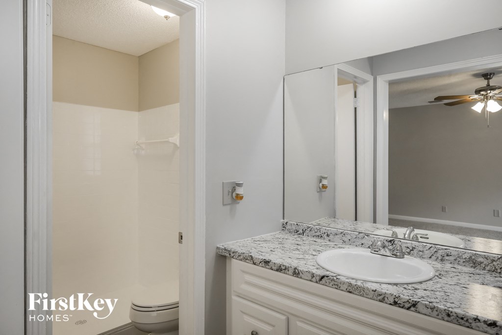 A bathroom with a marble countertop and a white sink.