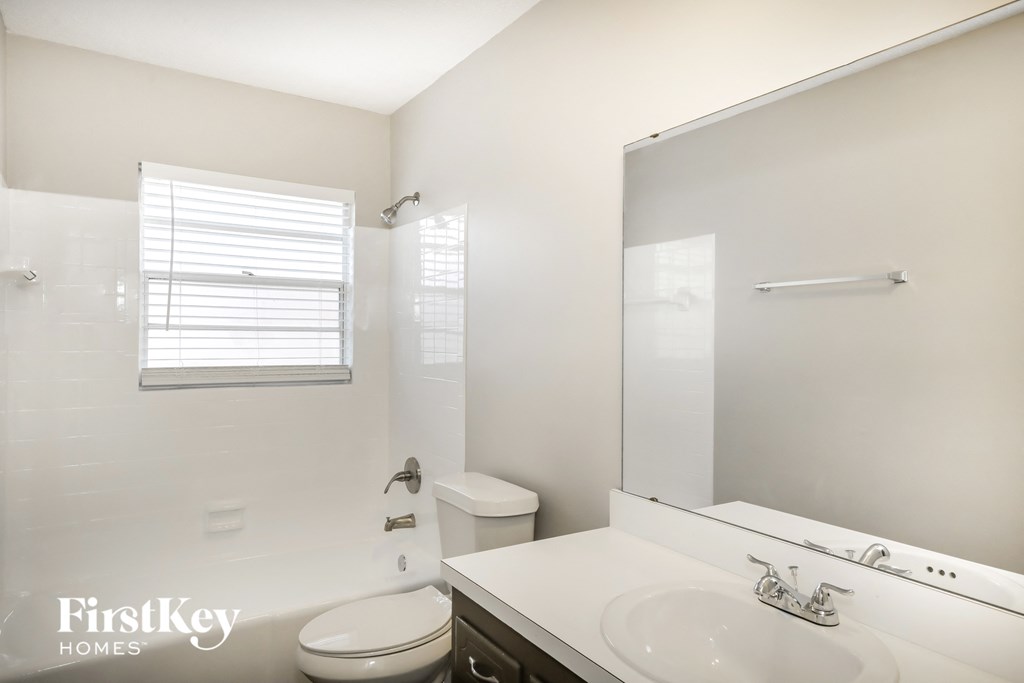 A white bathroom with a toilet, sink, and mirror.