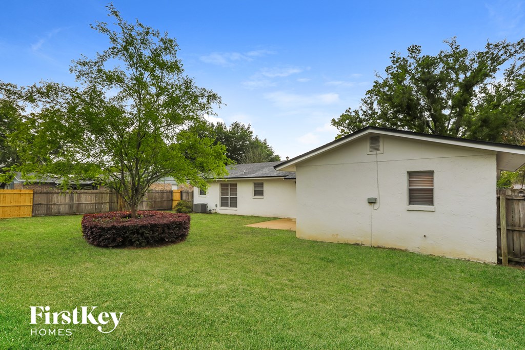 A small house with a white exterior and a brown fence.