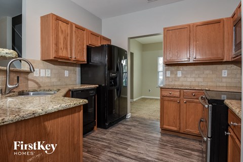 A kitchen with wooden cabinets and a black refrigerator.