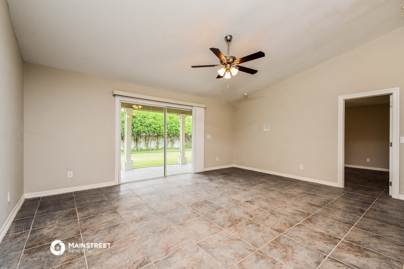 the empty living room with sliding glass doors to the backyard