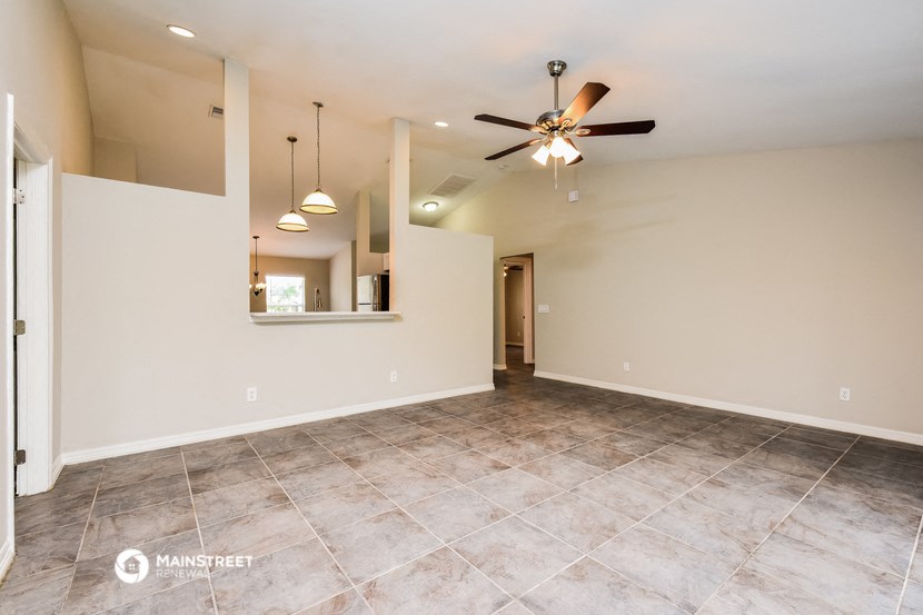 the spacious living room with tile flooring and a ceiling fan
