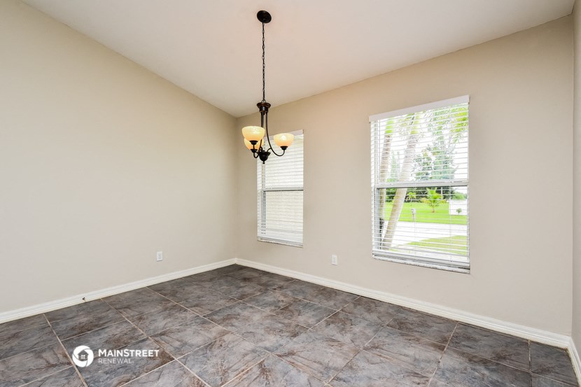 the spacious living room with large windows and tile flooring