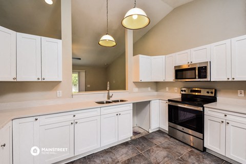 a large kitchen with white cabinets and black appliances