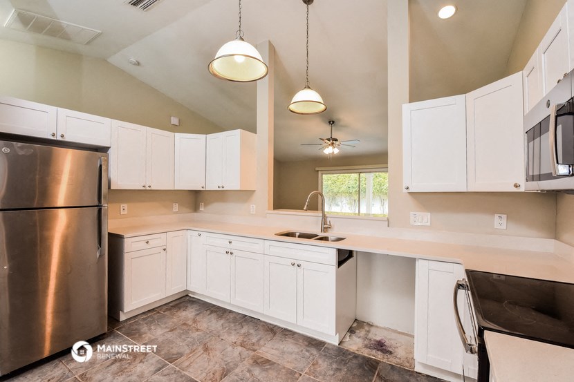a kitchen with white cabinets and a stainless steel refrigerator