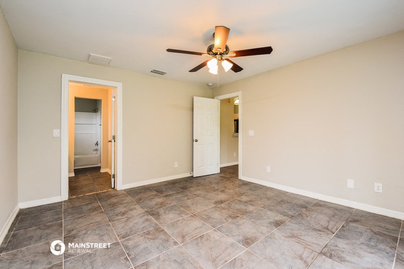 the spacious living room with tile flooring and a ceiling fan
