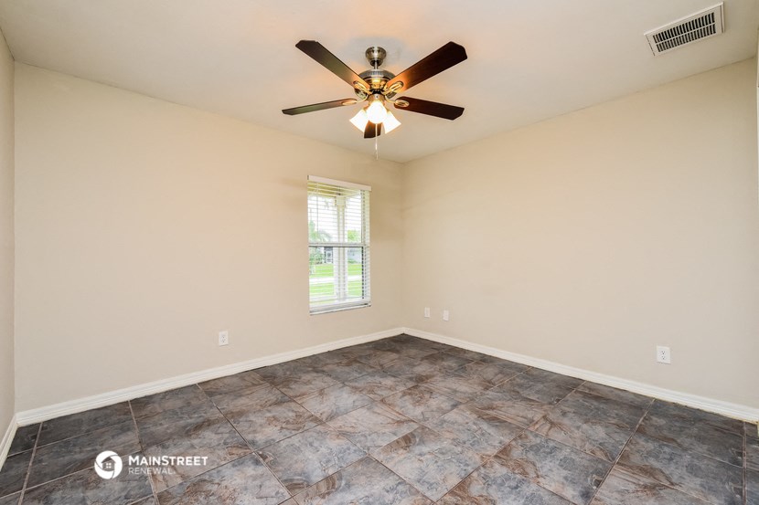 the spacious living room with ceiling fan and tile flooring