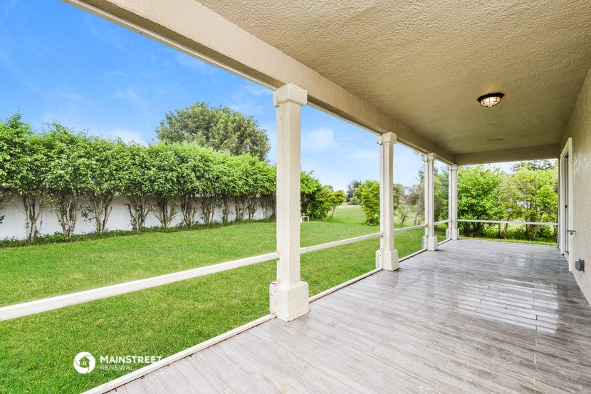 a porch with a view of the grass and a fence