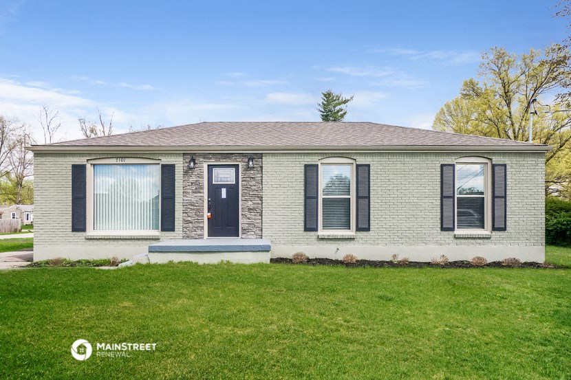 a white brick house with black shutters and a blue door