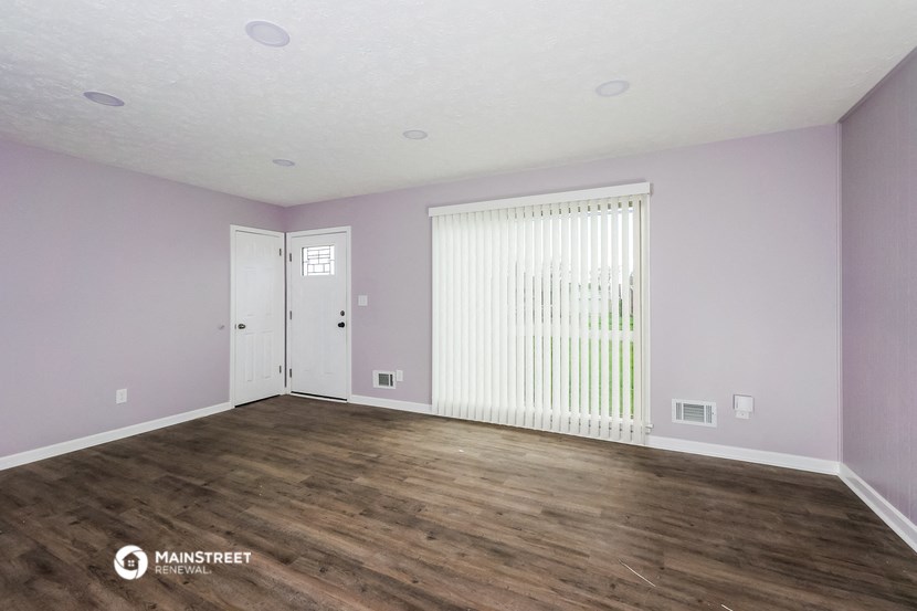 the living room of a house with purple and white walls and wood floors