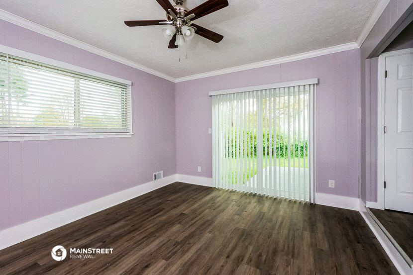 the living room of a home with purple walls and a ceiling fan