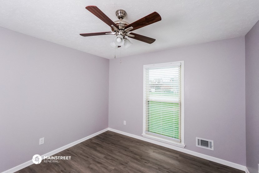 the bedroom has a ceiling fan and a large window