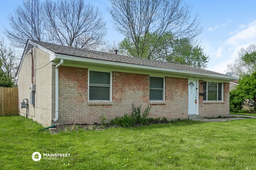 the front of a brick house with a green roof