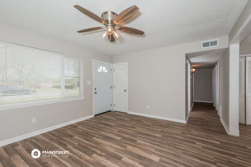 the living room of an empty house with a ceiling fan