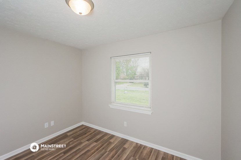 the interior of an empty room with wood flooring and a window