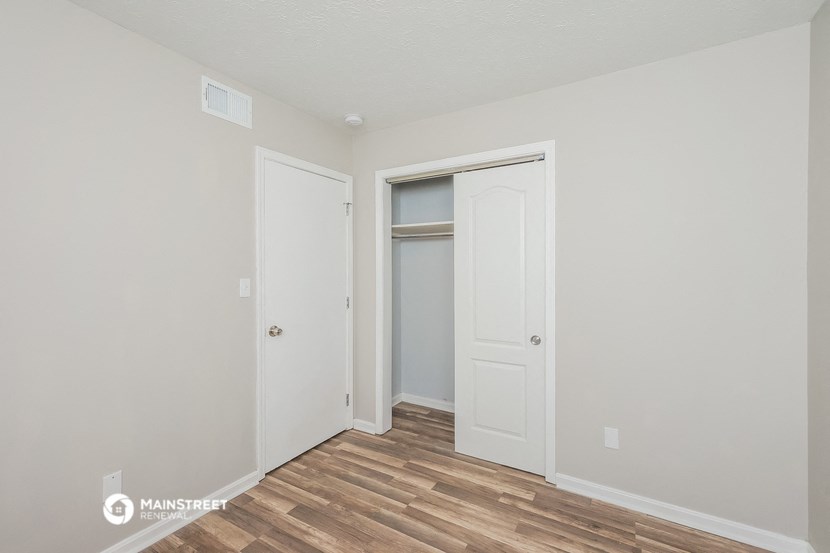a bedroom with a door to a closet and a hard wood floor