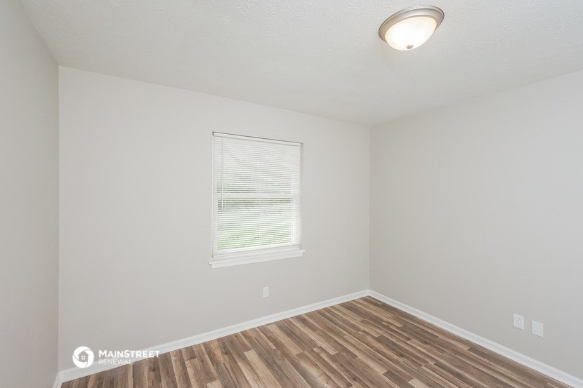 the interior of a bedroom with wood flooring and a window