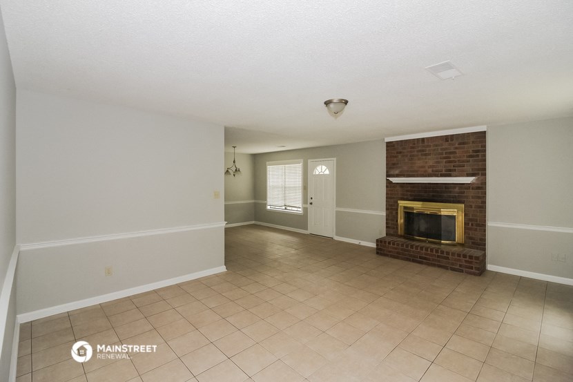 an empty living room with a brick fireplace and tiled floors
