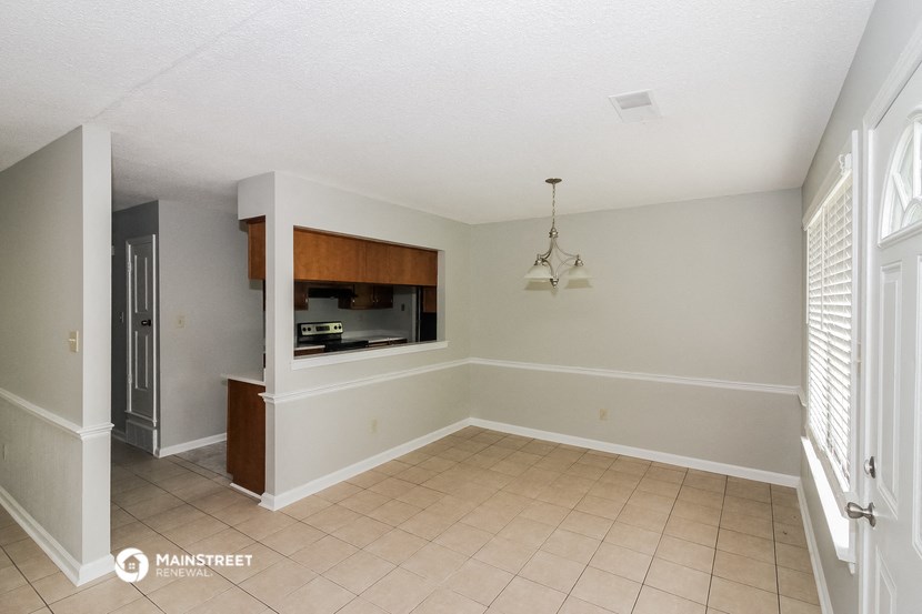 an empty living room with a kitchen and a window