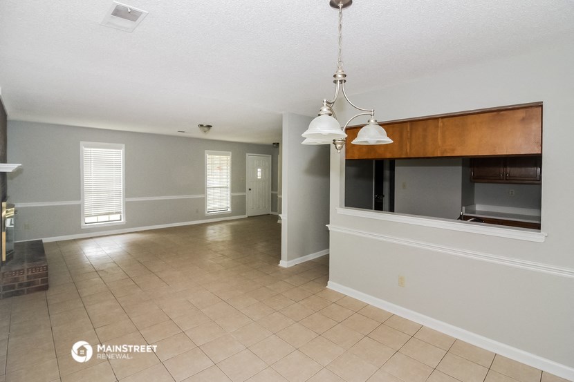 an empty living room with a large window and a tv