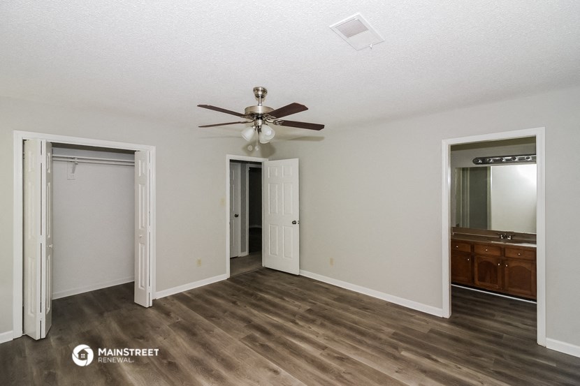 a living room with a ceiling fan and a door to a closet