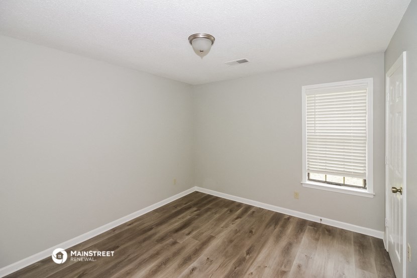 the spacious living room with hardwood flooring and a window