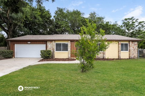 a brick house with a garage and a green lawn