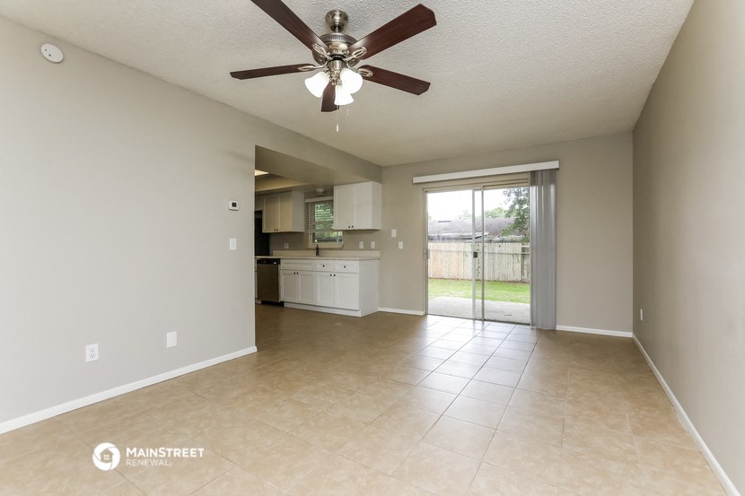 an empty living room and kitchen with a ceiling fan
