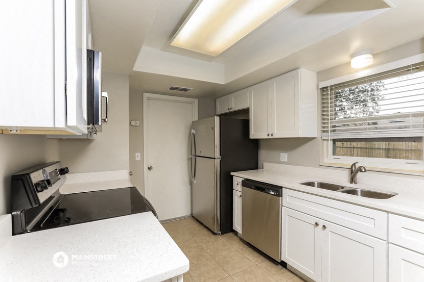 a kitchen with white cabinets and a stainless steel refrigerator