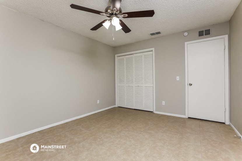 an empty living room with a ceiling fan and a closet